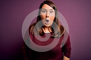 Beautiful brunette plus size woman wearing casual sweater over isolated purple background afraid and shocked with surprise