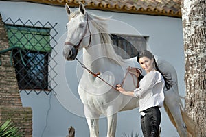 Beautiful brunette posing with beautiful white Andalusian stallion nearly stable. Spain, Andalusia