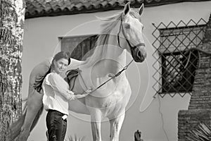 Beautiful brunette posing with beautiful white Andalusian stallion nearly stable. Spain, Andalusia