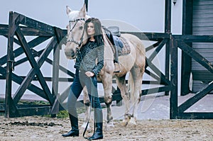 Beautiful brunette posing with a horse in the autumn afternoon at a country ranch. Lifestyle Photo. Fashion photo.