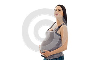 Beautiful brunette pregnant woman touching her belly and looking up isolated on white background