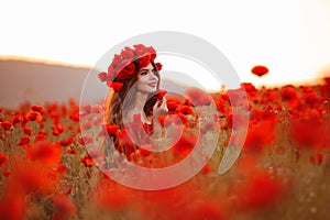 Beautiful brunette in red poppies field. Happy smiling teen girl portrait with wreath on head enjoying in poppy flowers nature