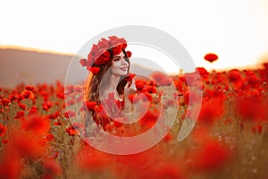 Beautiful brunette in red poppies field. Happy smiling teen girl portrait with wreath on head enjoying in poppy flowers nature bac