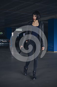 Beautiful brunette sexy spy agent killer or police woman in leather jacket and jeans with a gun in her hand running after