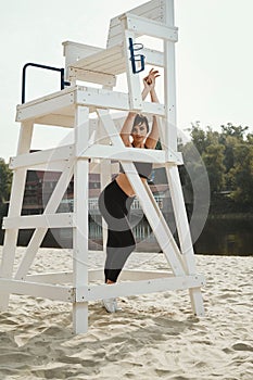 Beautiful brunette with short haircut poses on river beach