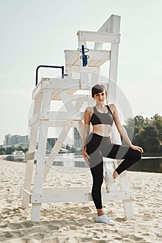 Beautiful brunette with short haircut poses on river beach