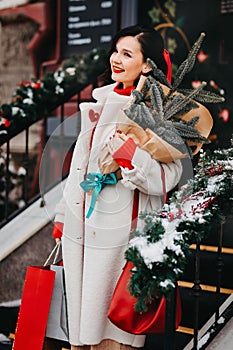 beautiful brunette on the stairs with shopping and a Christmas tree. winter city