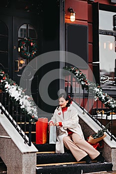 beautiful brunette on the stairs with shopping and a Christmas tree. winter city