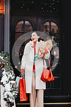 beautiful brunette on the stairs with shopping and a Christmas tree. winter city