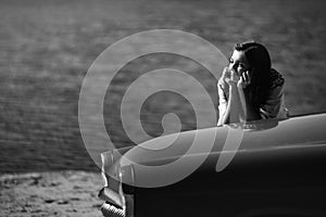 Beautiful brunette stylish bride dreaming on red vintage car near in a sunny lake, concept of happiness