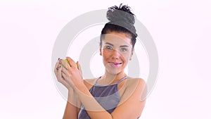 Beautiful brunette throws up green apple and laughing at white background