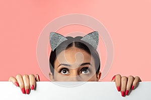 Beautiful brunette wearing cat ears glamour hoop on pink background. Creative holiday concept