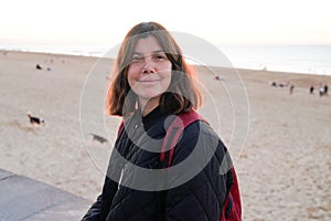 Beautiful brunette woman in casual winter jacket walking weekend on beach autumn coast