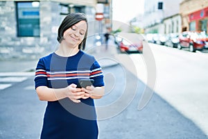 Beautiful brunette woman with down syndrome at the town on a sunny day using smartphone