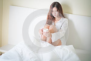 Beautiful brunette woman drinking and morning coffee in bedroom