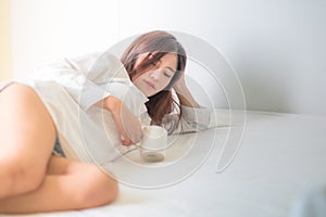 Beautiful brunette woman drinking and morning coffee in bedroom