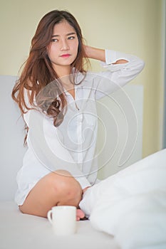 Beautiful brunette woman drinking and morning coffee in bedroom