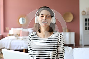 Beautiful brunette woman in earphones sitting on sofa listening to music with closed eyes