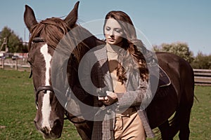 Beautiful brunette woman in an elegant checkered jacket with a horse