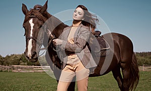 Beautiful brunette woman in an elegant checkered jacket with a horse