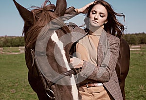 Beautiful brunette woman in an elegant checkered jacket with a horse