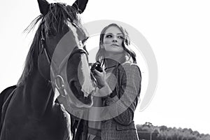 Beautiful brunette woman in an elegant checkered jacket with a horse