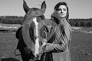 Beautiful brunette woman in an elegant checkered jacket with a horse