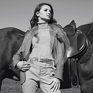 Beautiful brunette woman in an elegant checkered jacket with a horse