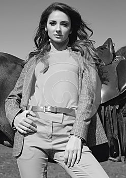 Beautiful brunette woman in an elegant checkered jacket with a horse