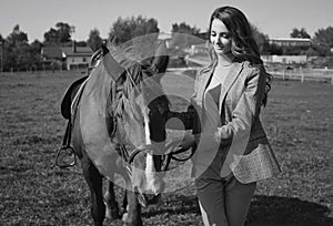 Beautiful brunette woman in an elegant checkered jacket with a horse