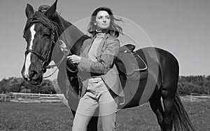 Beautiful brunette woman in an elegant checkered jacket with a horse