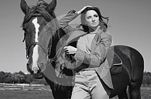 Beautiful brunette woman in an elegant checkered jacket with a horse
