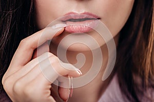 Beautiful brunette woman with a finger at her mouth on white background