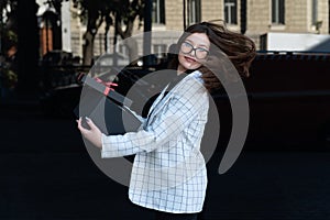 Beautiful brunette woman with gift in her hands on black background. Happy stylish woman with black box in hands