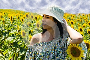 Beautiful brunette woman with hat in sunflower field