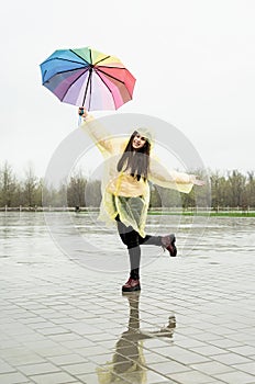 Beautiful brunette woman holding colorful umbrella out in the rain