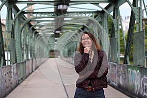 Beautiful brunette woman with leather jacket on an iron bridge