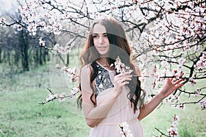 Beautiful brunette woman in the park standing near the blossom tree