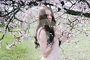 Beautiful brunette woman in the park standing near the blossom tree