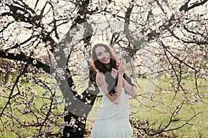 Beautiful brunette woman in the park standing near the blossom tree