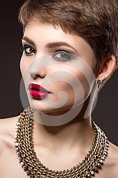 Beautiful brunette woman with perfect skin, bright makeup and gold jewelry. Beauty face.