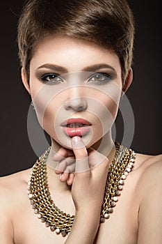 Beautiful brunette woman with perfect skin, bright makeup and gold jewelry. Beauty face.