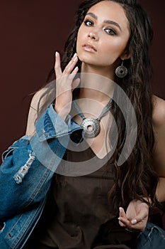 Beautiful brunette woman with perfect skin, bright makeup and jewelry. Beauty face. Picture taken in the studio on  brown