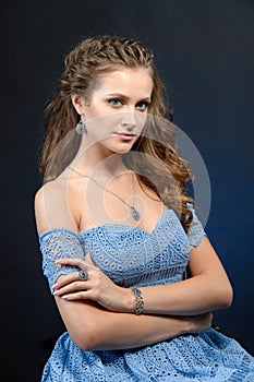 Beautiful brunette woman with perfect skin, bright makeup and jewelry. Beauty face. Picture taken in the studio on a dark blue ba