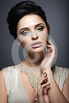 Beautiful brunette woman with perfect skin, gold makeup and handmade jewelry. Beauty face.
