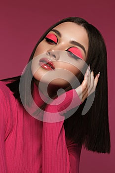 Beautiful brunette woman in pink clothes, with pink fashion make-up, posing in the studio. Beauty face.