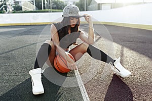 Beautiful brunette woman playing basketball on court outdoor