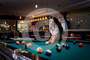 Beautiful brunette woman playing billiard in pub