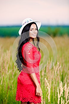 Beautiful brunette woman with a red dress in a field