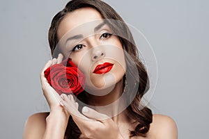 Beautiful brunette woman with red lipstick on lips. Close-up girl with rose.